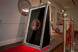 Photo booth magic mirror with red carpet and rope barriers at wedding reception.