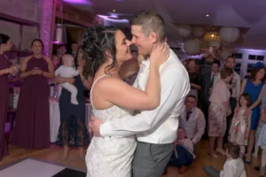 Bride and groom embrace during first dance at wedding reception. The guests are watching their special moment in awe.